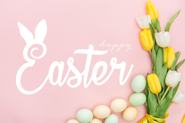 top view of painted chicken eggs and bright tulips on pink background with happy Easter lettering - Foto, afbeelding