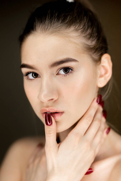 Retrato de una joven encantadora con maquillaje natural sosteniendo sus manos en su cara
 - Foto, Imagen