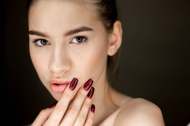Portrait of young brown-haired girl with natural makeup holding her fingers on her face - Photo, Image