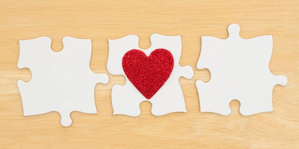 Three blank puzzle pieces with a heart on textured desk wood bac - Photo, Image