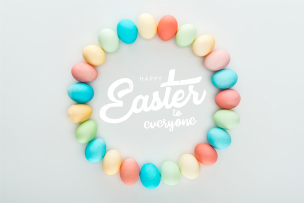 top view of round frame made of painted multicolored eggs with happy Easter to everyone white lettering - Photo, Image