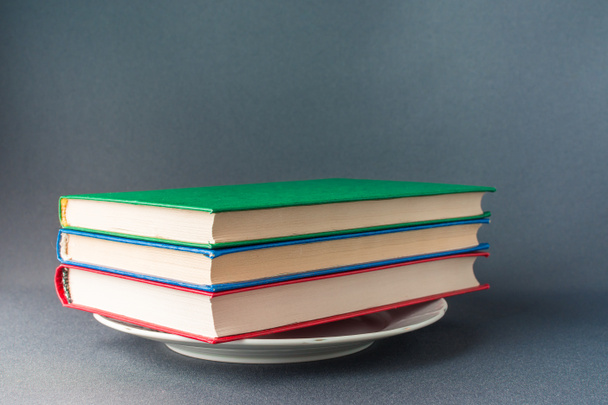 Renkli kitap yığını beyaz bir tabak üzerinde yatıyor - Fotoğraf, Görsel