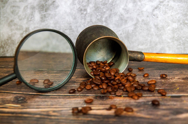 El hombre examina granos de café a través de una lupa. mano del hombre mantiene lupa sobre los granos de café
. - Foto, Imagen