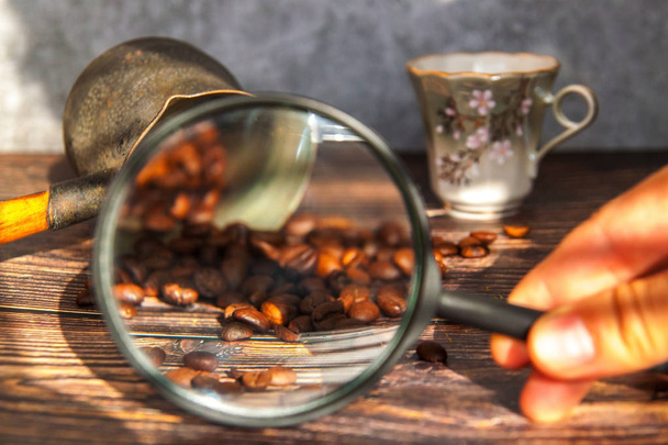 L'homme examine les grains de café à travers une loupe. main de l'homme garde loupe sur les grains de café
. - Photo, image