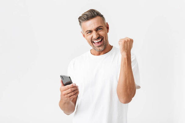 Image of cheery man 30s wearing casual t-shirt rejoicing while u - Фото, изображение