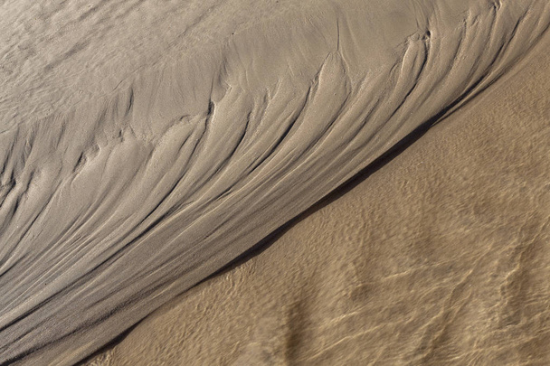 Textura natural en la arena de la playa dejada por el paso de agua que aún corre
. - Foto, imagen