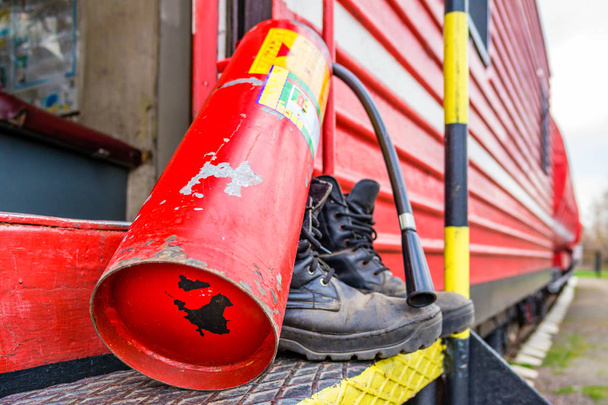 Stare buty strażackie na tle czerwonego pociągu pożarowego - Zdjęcie, obraz