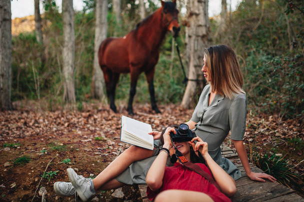 本を読んで森の中で写真を撮る若い女性 - 写真・画像