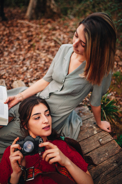 Νεαρές γυναίκες διαβάζουν ένα βιβλίο και βγάζουν φωτογραφίες στο δάσος - Φωτογραφία, εικόνα