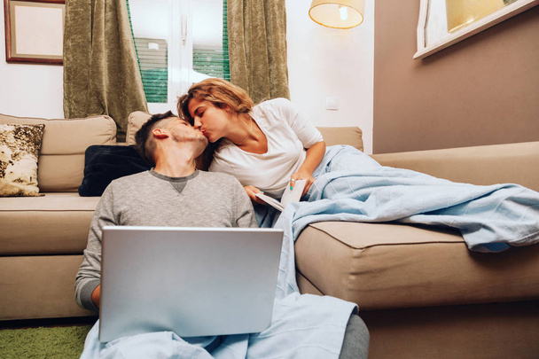 Nuori hymyilevä hetero pari yhdessä sohvalla
 - Valokuva, kuva