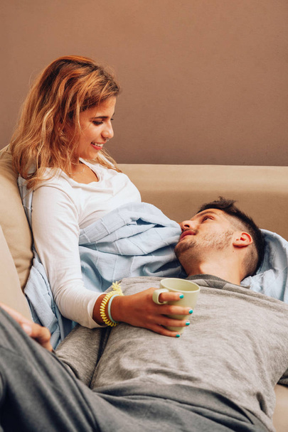 Young smiling couple together on sofa looking at each other - Фото, зображення