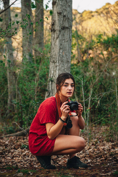 Jovem mulher tirando fotos na floresta usando um mini vestido
. - Foto, Imagem