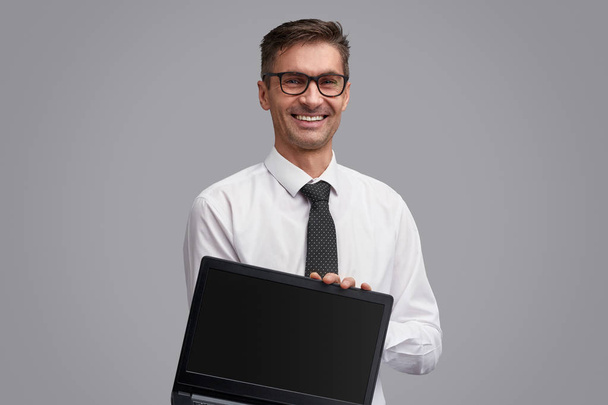 Iloinen liikemies esittelemässä kannettavaa tietokonetta
 - Valokuva, kuva