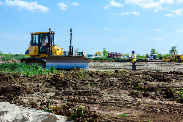 Bulldozer está nivelando el terreno en el sitio de construcción
 - Foto, imagen