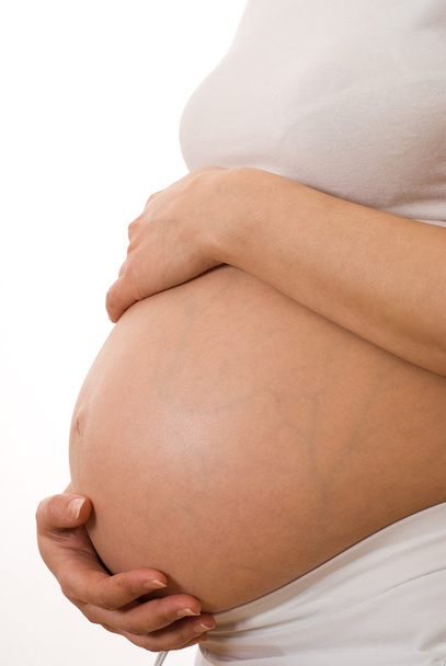 Pregnant woman holding hands on stomach - Фото, зображення