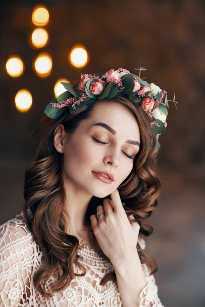 Young sensual beautiful woman with wreath of flowers in her hair dreaming with close eyes                               - Photo, Image