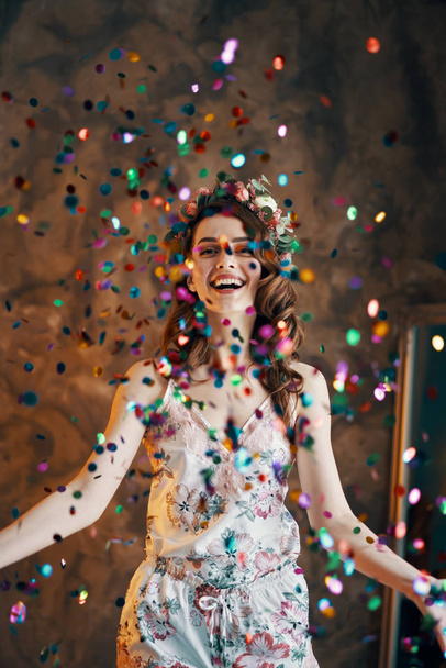 Happy beautiful woman celebrating with confetti falling everywhere on room. Celebration concept - Photo, Image