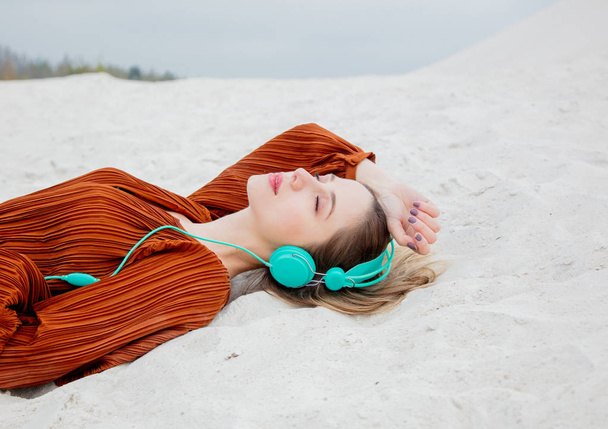 Young woman in burgundy color blouse with headphones lying down - Zdjęcie, obraz