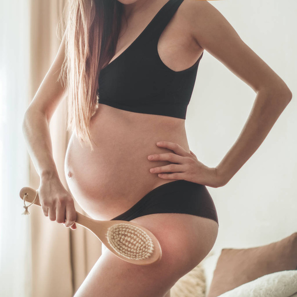 妊娠とドライマッサージ。彼女の足の上にドライブラシを保持している妊娠女性 - 写真・画像