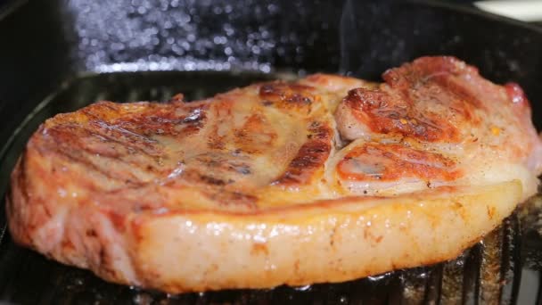 Steak de porc rôti dans une poêle à frire près vers le haut - Séquence, vidéo