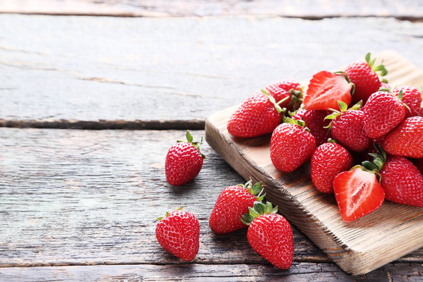 Fresh strawberries with cutting board on grey wooden table - Photo, Image