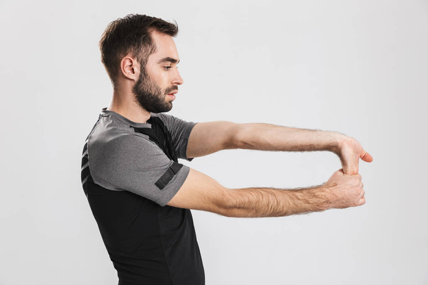 Young sports fitness man posing isolate over white wall background make stretching exercises. - Fotó, kép