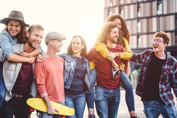 Group of young people having fun in the city center - Happy friends piggybacking while laughing and walking together outdoor - Friendship, millennial generation, teenager and youth lifestyle concept - Photo, Image