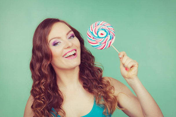 Smiling girl with lollipop candy on teal - Фото, зображення