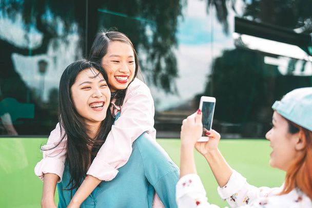 Millennial Asian dziewcząt przy pomocy zdejmowany telefon na wolnym powietrzu-młody szczęśliwy społeczeństwo mający zabawa z nowy smartphone aplikacja technologia zewnątrz-pojęcie od przyjaźń, technika i młodość nastolatków styl życia - Zdjęcie, obraz