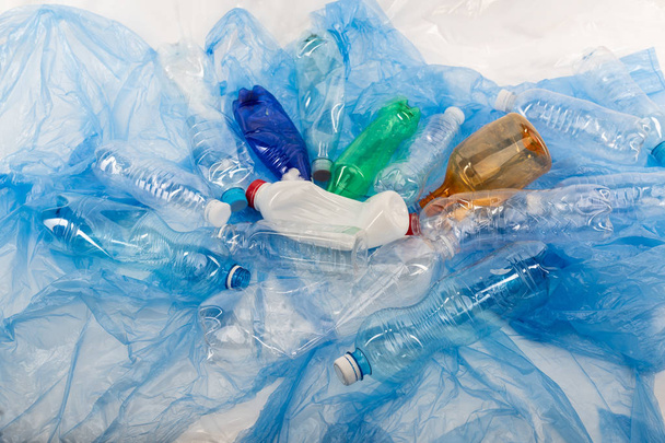 Bright various empty bottles being deformed and placed on plastic litter - Фото, изображение