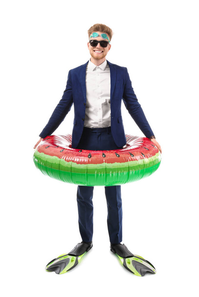Funny young tourist in suit and with inflatable ring and flippers on white background - Photo, Image