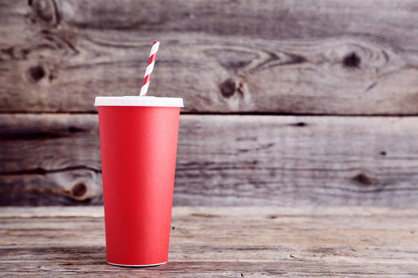 Red paper cup with straw on wooden table - Foto, immagini