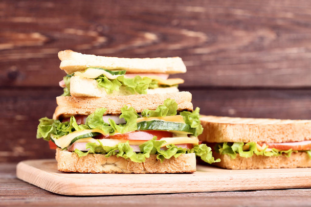 Tasty sandwiches with cutting board on brown wooden background - Fotografie, Obrázek