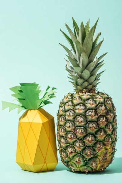 handmade paper pineapple with fresh whole pineapple on turquoise - Foto, imagen