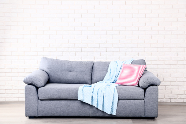 Soft pillow and plaid on grey sofa - Foto, afbeelding