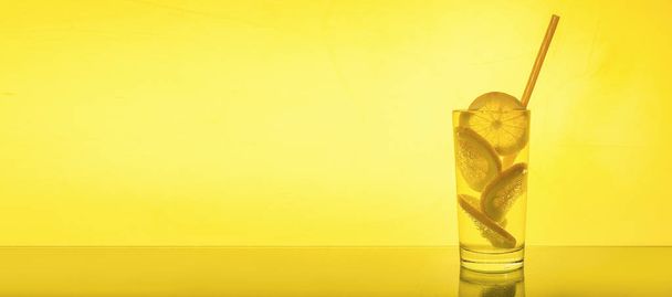 Pełna szklanka świeżej chłodnej przezroczystej wody z cytryną na żółto  - Zdjęcie, obraz
