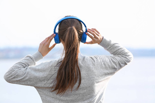 Genç kadın Nehri yakınında müzik dinlemek - Fotoğraf, Görsel