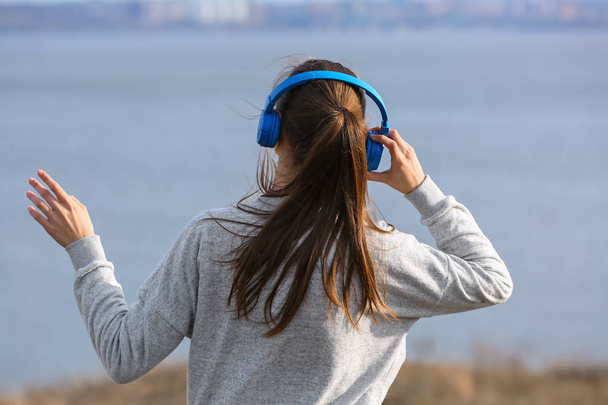 Genç kadın Nehri yakınında müzik dinlemek - Fotoğraf, Görsel