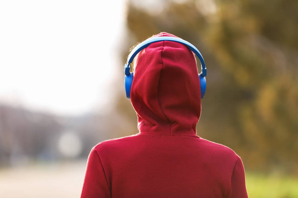 Young woman listening to music in park - Fotoğraf, Görsel