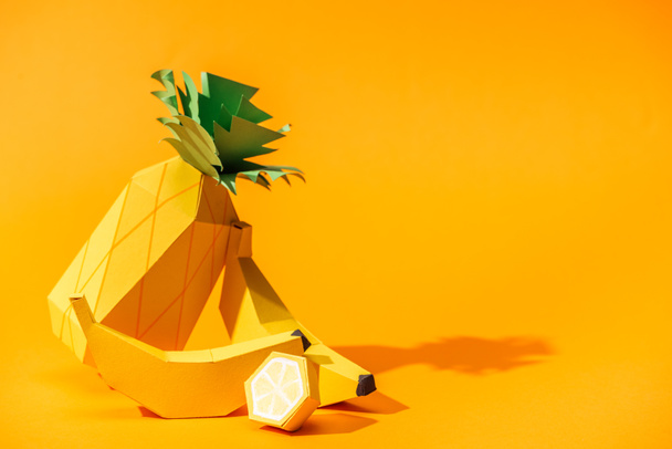 handmade paper pineapple, bananas and lemon on orange with copy space - Zdjęcie, obraz