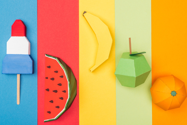 top view of various origami fruits and ice cream on colorful paper stripes - Фото, изображение