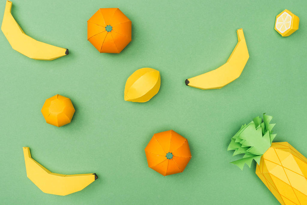 top view of handmade paper bananas, lemons and tangerines isolated on green - 写真・画像