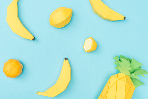 青で分離された手作りの紙のレモン、バナナ、パイナップルのトップビュー - 写真・画像
