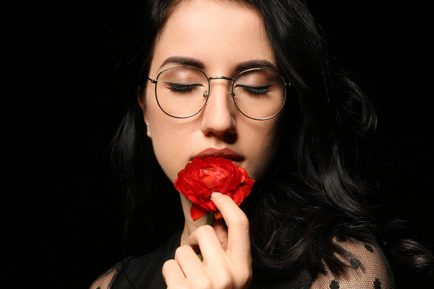 Portrait of beautiful woman with flower on dark background - Foto, imagen