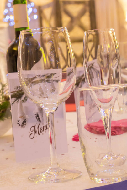 Receptie en feesttafel, met wijnglas, waterglas en champagneglas, menu en fles wijn - Foto, afbeelding