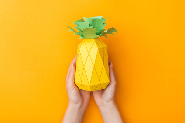 partial view of young woman holding paper pineapple isolated on orange - Photo, Image