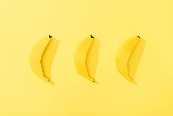 top view of handmade paper bananas arranged in row on yellow - Foto, afbeelding