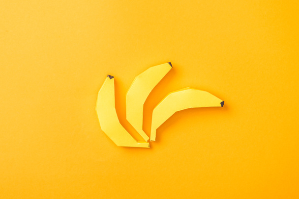Top zicht op geel papier bananen op oranje - Foto, afbeelding