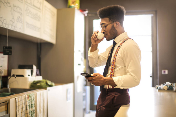 Businessman drinking coffee while checking his phone - Photo, Image