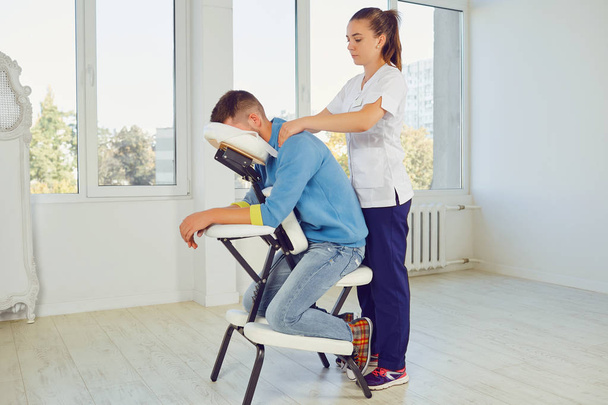 Woman massaging man in special stand - Foto, Bild